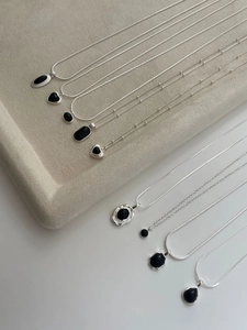 Macro detail of S925 silver necklaces with black agate pendants in various shapes