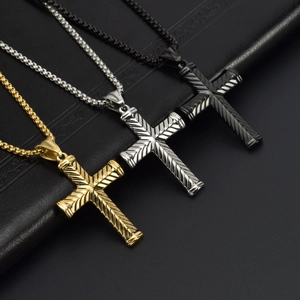 Trois colliers croix en métal or, argent et noir sur fond de cuir noir élégant et moderne