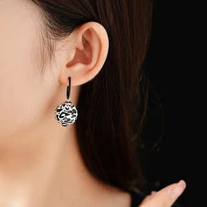 Close-up of black and white leopard print ball earring worn by a model in detail view