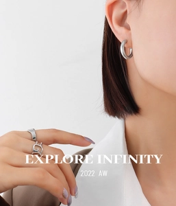 Detail view of silver C-shape earrings and minimalist geometric rings on model