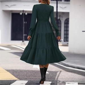Detail view of the smocked back and tiered skirt of an elegant dark green midi dress