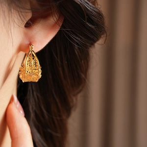 Close-up of golden hollow geometric flower earrings with intricate mesh craftsmanship
