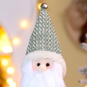 Detail of green knitted hat with bell and white beard on a Christmas gnome doll