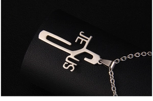 Macro shot of polished stainless steel Jesus cross pendant on black leather background