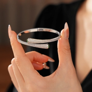 Detailed macro view of silver open bangle featuring sparkling pavé cubic zirconia and green gems