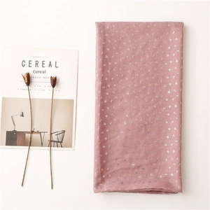 Detail of dusty pink scarf featuring gold clover foil prints and textured fabric texture