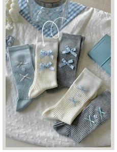 Flat lay of ribbed ballet style socks in blue, white, and grey with silk ribbon bows
