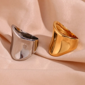 Polished silver and 18K gold irregular geometric rings on beige silk fabric background