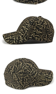 Detail of black and gold monogram baseball cap showing premium jacquard texture and buckle