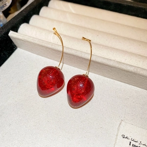 Gros plan sur les boucles d'oreilles fraise en résine rouge et crochets dorés