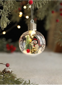 Close-up of glowing Christmas bulb ornament with miniature snowman and LED lights inside