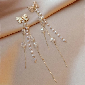 Detail of elegant bow earrings with pearls and long crystal fringe on gold silk