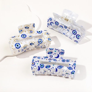 Close-up of three PVC hair claws with evil eye patterns and bohemian gold star details
