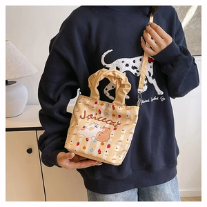 Detail of a beige canvas bucket bag with floral patterns and a cartoon cat print