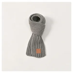 Detailed view of light gray knit scarf texture with embossed brown leather label