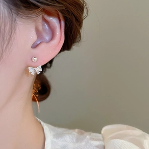 Detail of silver bow earrings with sparkling cubic zirconia on a real model