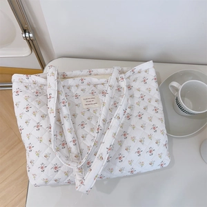 Détail du sac cabas matelassé à fleurs avec étiquette en texte français et texture souple