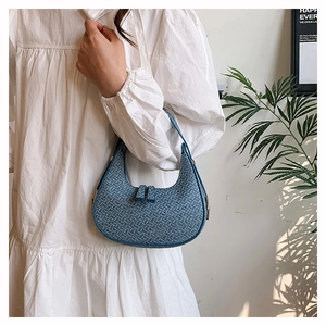 Detailed view of dark blue woven denim shoulder bag on a clean white aesthetic background