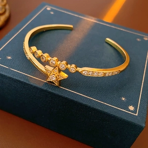 Macro detail of gold plated star bangle with sparkling zircon stones on luxury navy display