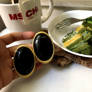 Close-up of vintage black oval earrings with matte gold frame in a lifestyle setting