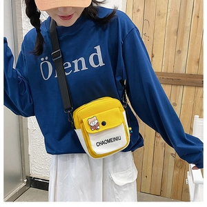 Detail of yellow and white canvas crossbody bag featuring flip-top design and badges