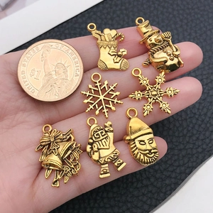 Golden Christmas charms set with snowman and snowflake designs shown with a dollar coin