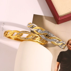 Detail of 18K gold plated bangle with eye zircon buckle on a white display stand
