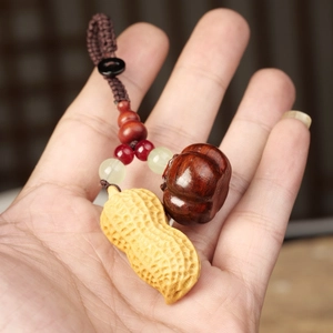 Macro detail of hand-carved wood peanut and persimmon charm with woven cord