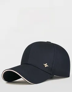 Detail of navy business baseball cap with gold metal logo and contrast brim trim