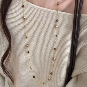 Vintage long necklace with tiger eye stones and pearls on elegant beige knitwear