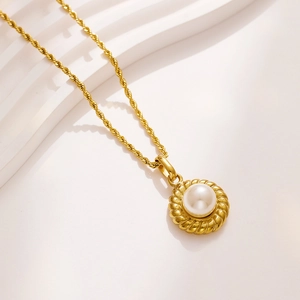 Detailed macro view of a vintage faux pearl pendant on a gold titanium twist chain