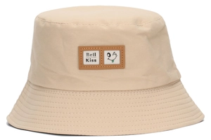 Close-up of beige cotton bucket hat featuring a smiley face patch and letter embroidery