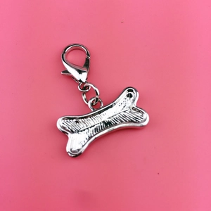 Detail of a textured silver metal dog bone pendant with lobster clasp on pink background