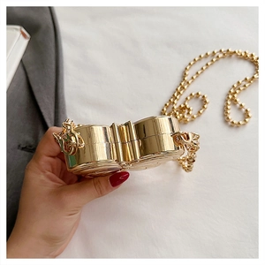 Close-up of golden metal mini box bag featuring decorative butterfly design and bead chain
