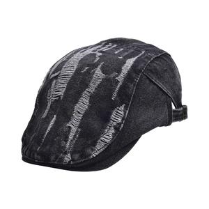Detailed view of distressed black denim flat cap with vintage frayed holes and metal buckle