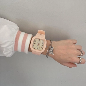 Pink square digital watch with silicone strap and silver bracelet on a wrist