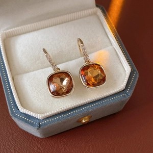 Gros plan de boucles d'oreilles dorées avec pierres ambrées dans un écrin bleu