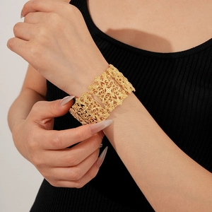 Macro shot of gold-plated hollow floral pattern on a wide vintage-style cuff bracelet