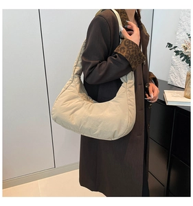 Détail d'un sac à bandoulière matelassé beige en croissant avec texture en nylon