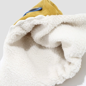 Detail of yellow corduroy fabric with warm white sherpa fleece lining on a winter hat