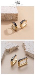 Detail of gold geometric earrings with black rectangular inlay on minimalist display