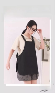 Detail of black water-repellent canvas work apron featuring adjustable straps and dual-wear design