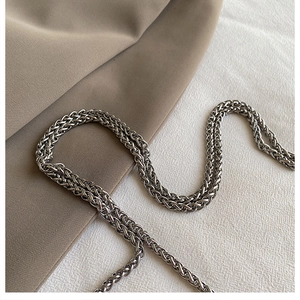 Detailed view of a stylish silver metal chain strap on beige fabric for a crossbody bag