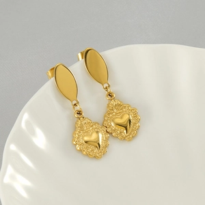 Boucles d'oreilles pendantes cœur vintage en acier titane doré sur un plat en coquillage