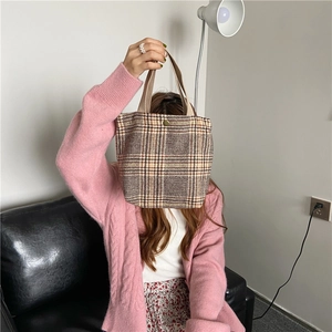 Detail of the vintage plaid canvas handbag with a metal button and durable top handle