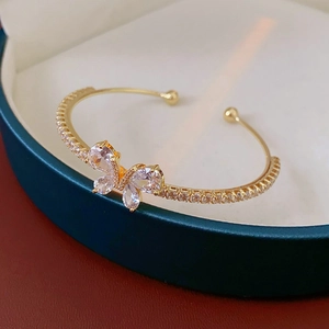 Vue macro d'un bracelet papillon doré avec zircons sur un écrin à bijoux vert
