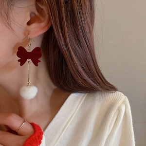 Detailed view of model wearing red flocked bow earrings with white pom-poms