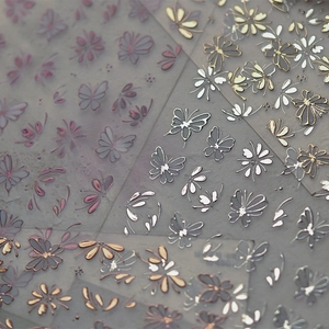 Detail of gold and silver nail stickers with elegant floral and butterfly motifs