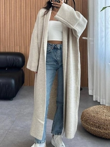 Détail d'un long cardigan en maille beige avec une coupe ample et une texture d'hiver douce