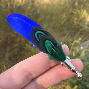 Elegant peacock feather brooch with vibrant blue tones and silver pin for formal suits